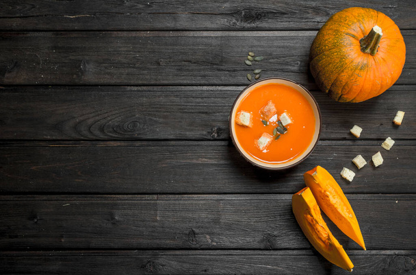 Pumpkin soup in bowl with rusks and whole pumpkin. On wooden background - Foto, immagini