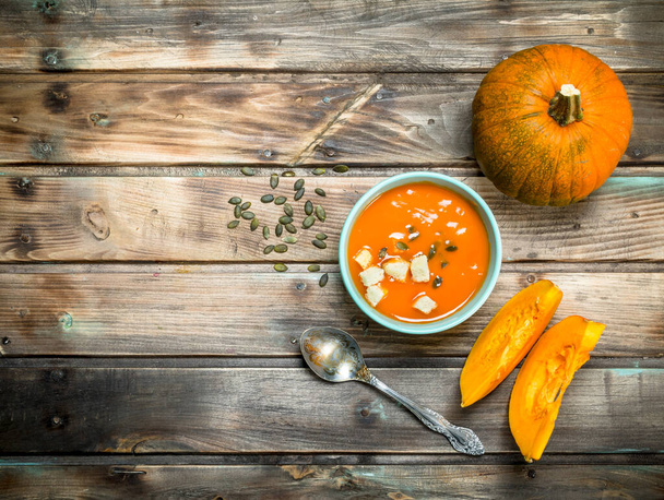 Pumpkin soup in bowl with spoon. On wooden background - Photo, image