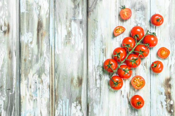 Tomatoes on a branch and pieces of fresh tomatoes. On white wooden background - Foto, Bild