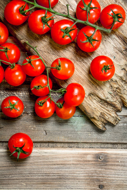 Los tomates maduros en la tabla de cortar. Sobre fondo de madera
 - Foto, Imagen