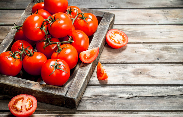 Fragrant red tomatoes on tray. On wooden background - Foto, afbeelding