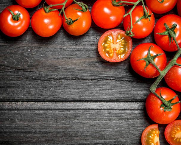 Red tomatoes on a branch. On wooden background - 写真・画像
