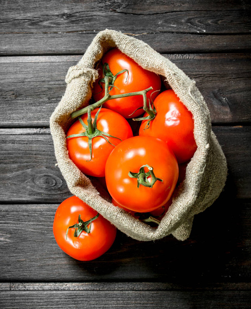 Red tomatoes in the sack. On wooden background - Foto, Bild