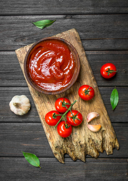 Kesme tahtası üzerinde bir kapta domates sosu. Ahşap arka plan üzerinde - Fotoğraf, Görsel