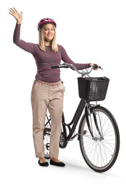 Young woman with a helmet standing with a bicycle and waving isolated on white background - Fotoğraf, Görsel