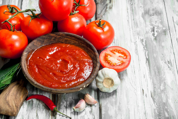 Tomato sauce in bowl and ripe tomatoes. On wooden background - Фото, зображення