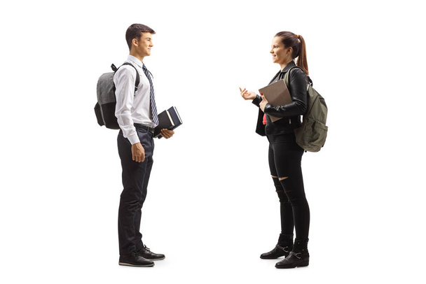 Full length profile shot of a male and female teenage students having a conversation isolated on white background - Foto, afbeelding