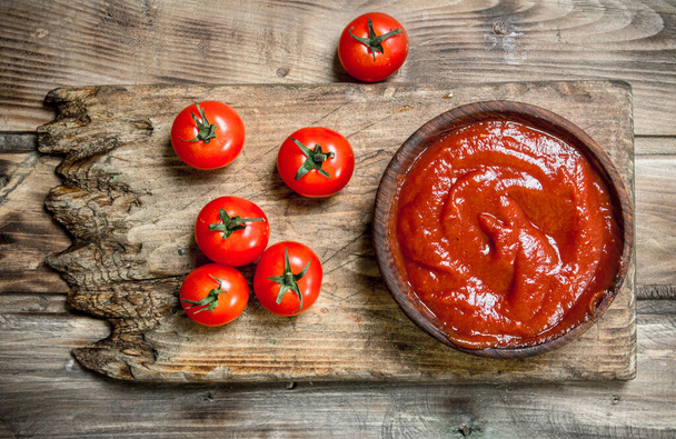 Tomato sauce in bowl on cutting Board. On wooden background - Foto, immagini