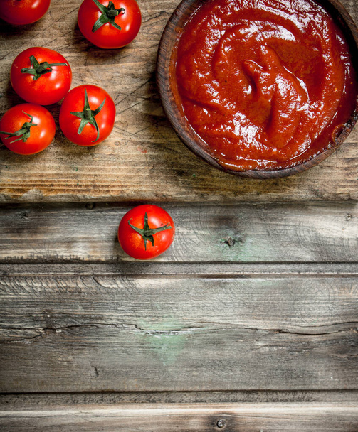 Tomato sauce in bowl on cutting Board. On wooden background - Фото, зображення
