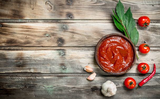 Tomato sauce in bowl with Bay leaf, garlic and tomatoes. On wooden background - Φωτογραφία, εικόνα