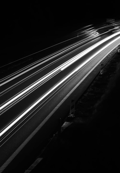 黒い背景の車のライトの白い線 - 写真・画像