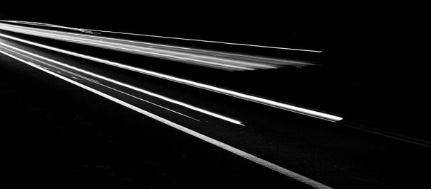 黒い背景の車のライトの白い線 - 写真・画像