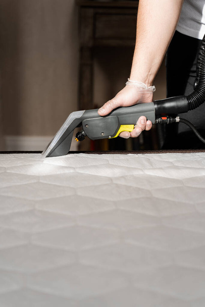 cleaner is extracting dirt from mattress using dry cleaning extractor machine. Cleaning mattress using extractor machine for dry clean at home - Valokuva, kuva