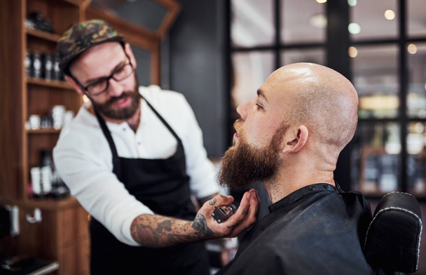 Respect the beard. a handsome young barber trimming and lining up a clients beard inside his barbershop - Photo, Image