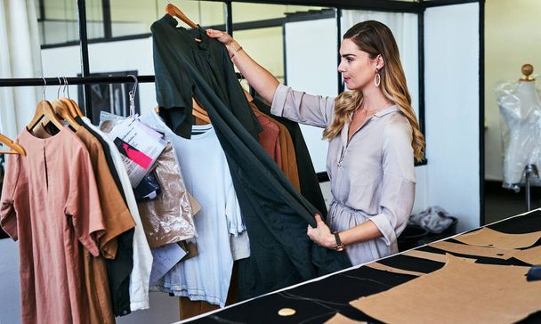 You are capable of greatness. a designer looking at garments in her workshop - Foto, Imagem