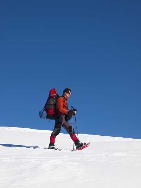 Ο άνθρωπος με χιονοπέδιλα στα βουνά. - Φωτογραφία, εικόνα