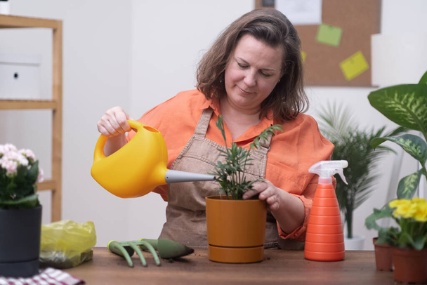 Eine Frau pflegt ihre Pflanzen mit Sorgfalt und Aufmerksamkeit und benutzt eine Gießkanne, um sie zu hydratisieren und das Wachstum zu fördern.  - Foto, Bild