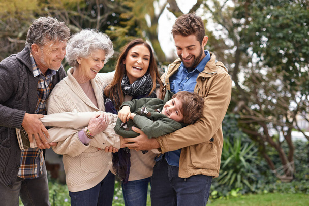 Family, child and grandparents or parents playing with kid in a park on outdoor vacation, holiday and excited together. Backyard, happiness and people play as love, care and bonding in nature. - Foto, imagen