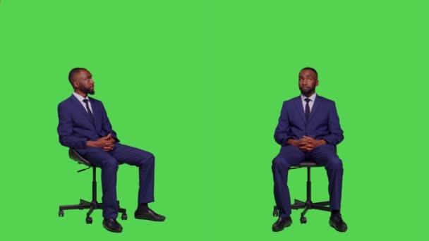 Ein männlicher Unternehmer sitzt auf einem Stuhl im Studio, trägt einen Business-Anzug und posiert über einem grünen Bildschirm. Junge Büroangestellte zuversichtlich vor der Kamera, Unternehmensmanagerin. - Filmmaterial, Video