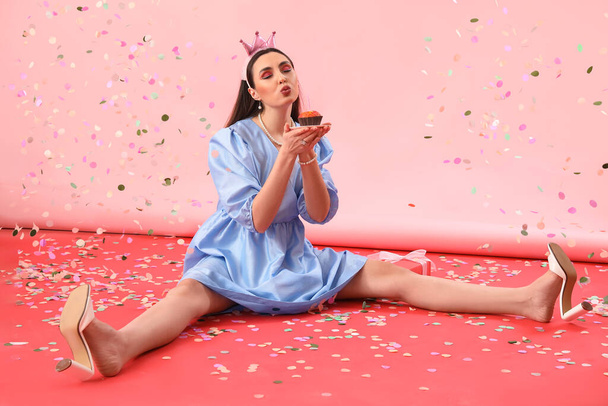 Happy young woman with Birthday cupcake on pink background - Φωτογραφία, εικόνα