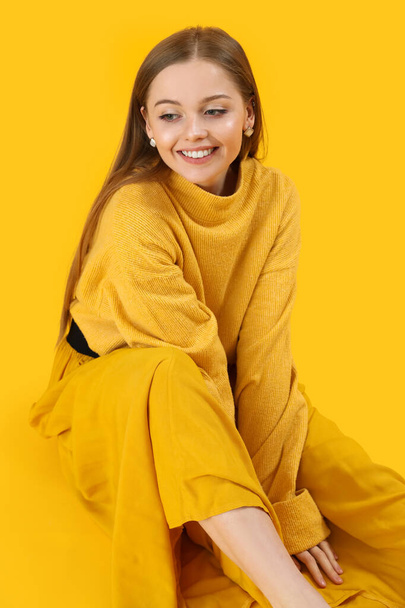 Fashionable young woman in knitted sweater and skirt on yellow background - Fotoğraf, Görsel