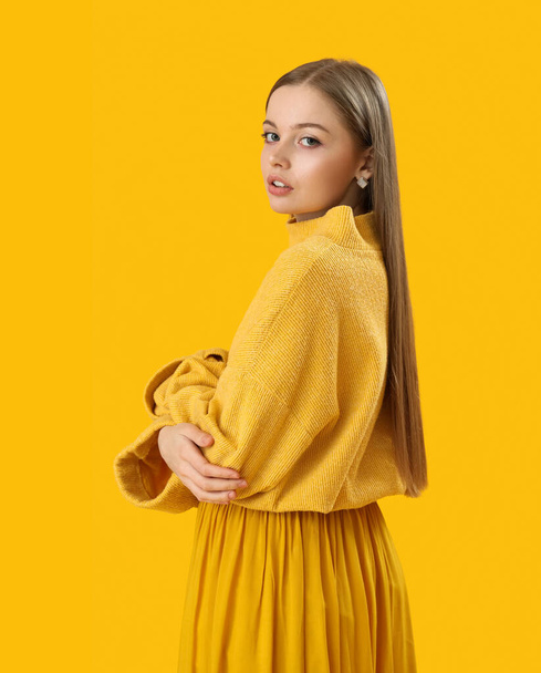 Fashionable young woman in knitted sweater and skirt on yellow background - Foto, Bild