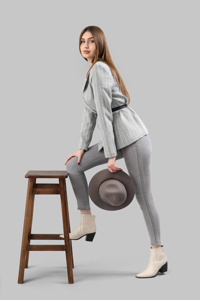 Stylish young woman near stool on grey background - Foto, Imagem