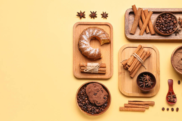 Composition avec bâtonnets de cannelle, grains de café, étoiles d'anis, gâteau et biscuits sur fond jaune - Photo, image