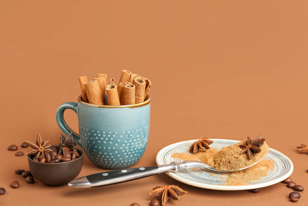 Plate with cinnamon powder, sticks, anise stars and coffee beans on color background - Photo, Image