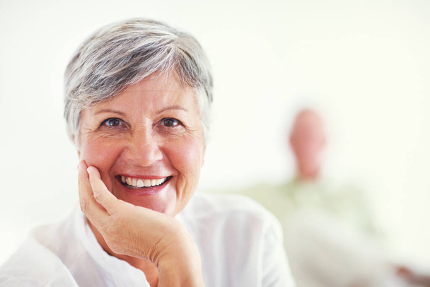 Mature woman smiling with man in background. Portrait of relaxed mature woman smiling with blurred man in background - Foto, immagini