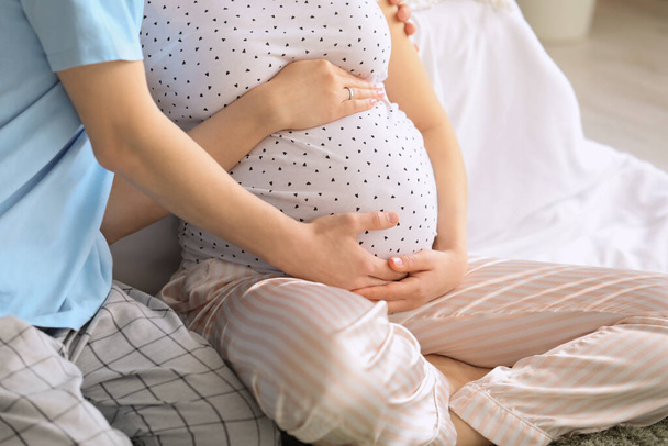Молодая беременная пара сидит в спальне, крупным планом - Фото, изображение