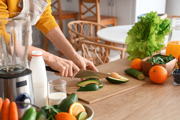 Reife Frau schneidet Avocado für gesunden Smoothie in der Küche, Nahaufnahme - Foto, Bild