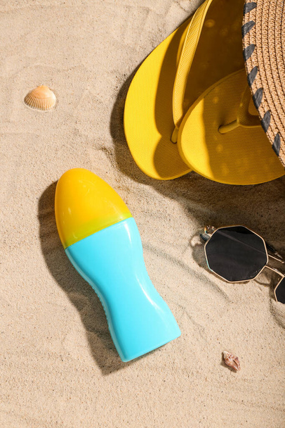 Composition créative avec bouteille de crème solaire et accessoires de plage sur sable - Photo, image