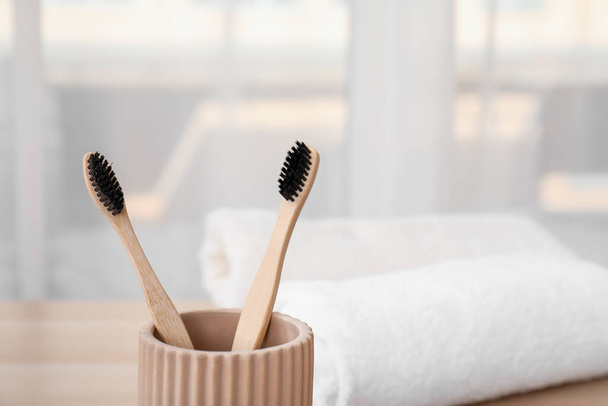 Porte-dents avec brosses à dents en bambou sur la table dans la chambre, gros plan - Photo, image