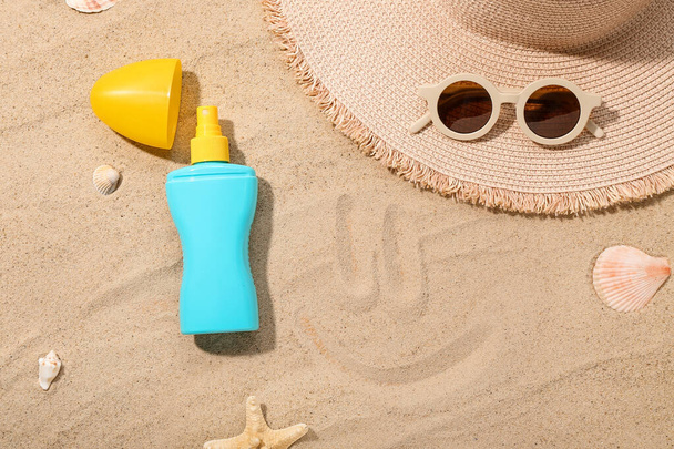 Creative composition with sunscreen cream, summer hat and sunglasses on sand - Foto, Imagen