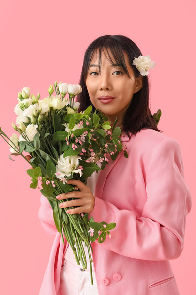 Gyönyörű ázsiai nő gazdaság csokor eustoma virágok rózsaszín háttér - Fotó, kép