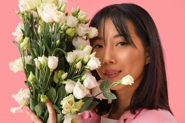 Beautiful Asian woman holding bouquet of eustoma flowers on pink background - Foto, immagini