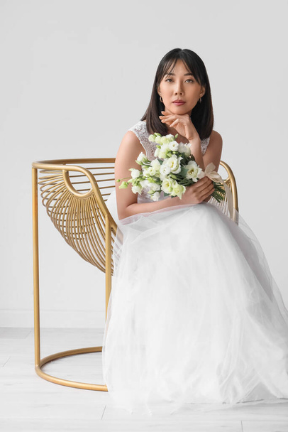Schöne junge asiatische Braut mit einem Strauß Eustoma-Blumen auf weißem Hintergrund - Foto, Bild