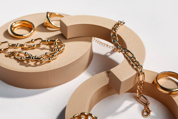 Díszítő dobogók arany gyűrűkkel és karkötőkkel fehér alapon - Fotó, kép