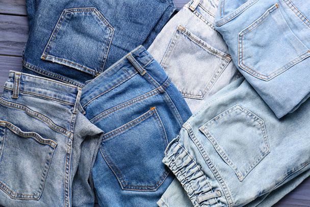 Различные стильные джинсы джинсы на синем деревянном фоне - Фото, изображение