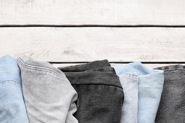 Différents jeans en denim élégant sur fond en bois, gros plan - Photo, image