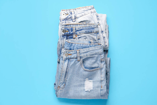 Different stylish jeans on blue background - Foto, Imagen
