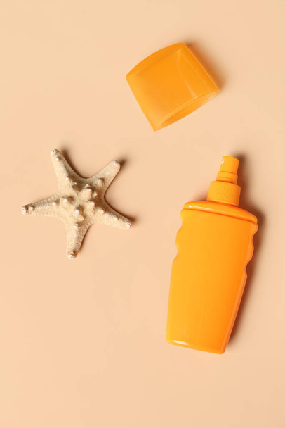 Μπουκάλι αντηλιακής κρέμας με αστερία σε ανοιχτό πορτοκαλί φόντο - Φωτογραφία, εικόνα