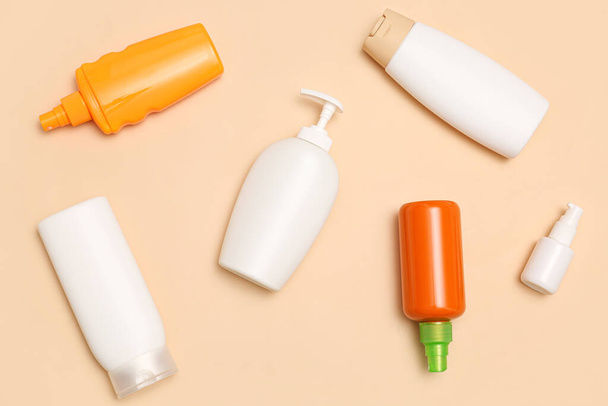 Different bottles of sunscreen cream on pale orange background - Foto, Imagem
