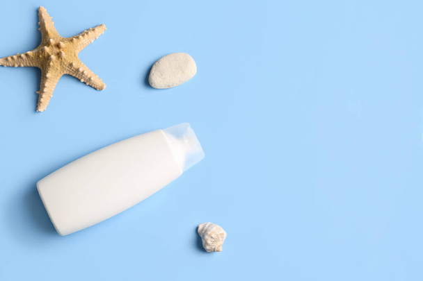 Bottle of sunscreen cream with seashells and starfish on blue background - Photo, Image