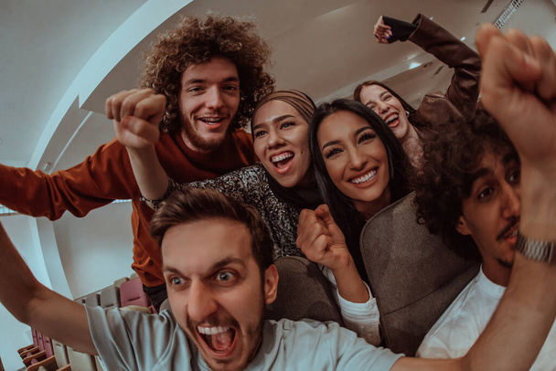In a heartwarming scene, a diverse group of friends gathers around a television, radiating joy and unity as they collectively witness and celebrate a joyful event together - Photo, Image