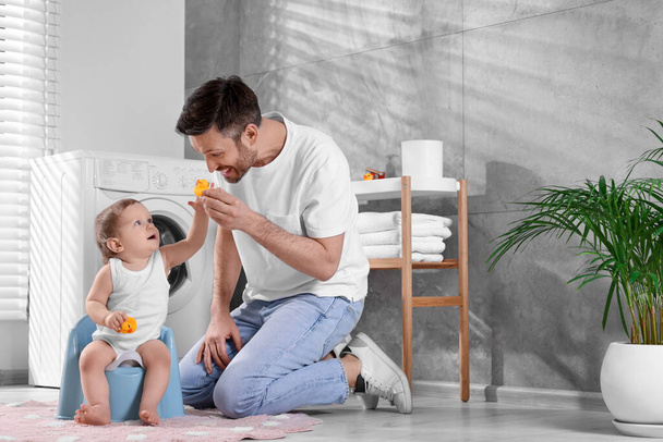 Father training his child to sit on baby potty indoors. Space for text - Foto, imagen