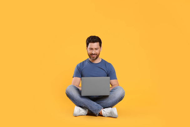 Happy man with laptop on yellow background - Foto, imagen