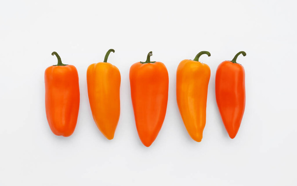 Fresh raw orange hot chili peppers on white background, flat lay - Fotoğraf, Görsel