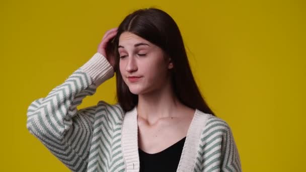 4k video jedné dívky dotýkající se svými vlasy a přemýšlející o něčem přes žluté pozadí. Pojetí emocí. - Záběry, video